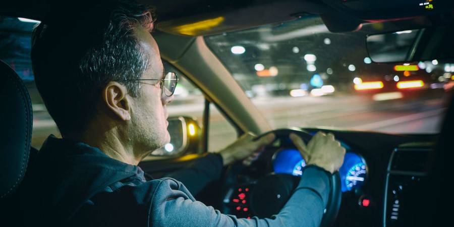 Un homme conduisant une voiture la nuit